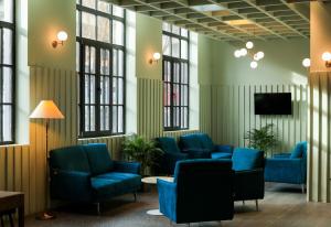 a waiting room with blue chairs and a tv at Pine Astoria Hotel in Tbilisi City