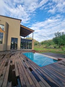a house with a wooden deck and a swimming pool at Pilanesberg Private Lodge in Pilanesberg