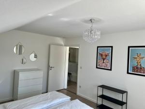 a white bedroom with a bed and a chandelier at Mühlbachs 2 in Kaufbeuren