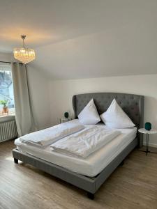 - un lit avec des draps et des oreillers blancs dans une chambre dans l'établissement Mühlbachs 2, à Kaufbeuren