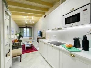 a kitchen with white cabinets and a living room at Juderia de Sevilla VI Luxury Apartments in Seville