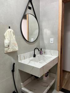 ein Bad mit einem Waschbecken und einem Spiegel in der Unterkunft Casa Confortável e Aconchegante in Brotas