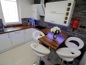 a kitchen with a wooden table and white chairs at Private Room in Modern Apartment in Aberdeen