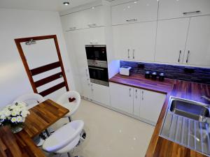 アバディーンにあるPrivate Room in Modern Apartmentの白いキャビネット、木製テーブルと椅子付きのキッチンが備わります。