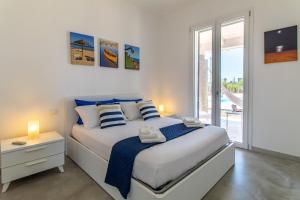 a white bedroom with a bed and a window at Villa Verde Oliva in Ispica