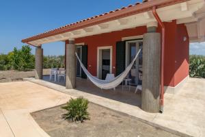 a red house with a hammock on a patio at Villa Verde Oliva in Ispica
