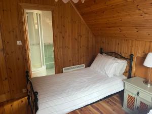 a bedroom with a bed in a wooden room at Large Newly Refurbished Lakeside Chalet With Optional Hot Tub & Boat Hire in Duneena