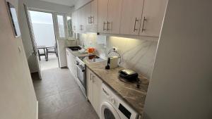 a kitchen with white cabinets and a washer and dryer at Angelos House Deluxe Apartments in Skiathos