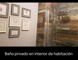 uma casa de banho com um chuveiro com imagens na parede em Habitación suite con baño a pies del río Guadalquivir em Coria del Río