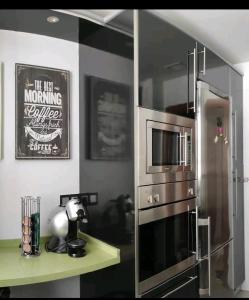 uma cozinha com um frigorífico de aço inoxidável e um micro-ondas em Habitación suite con baño a pies del río Guadalquivir em Coria del Río