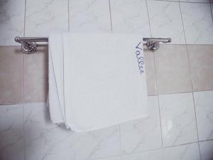 - une serviette blanche suspendue à un porte-serviettes dans la salle de bains dans l'établissement HOTEL DE LA VALLEE NEW, à Yaoundé