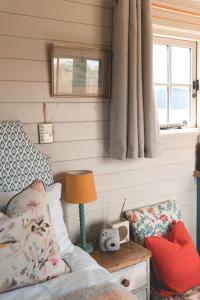 a living room with a couch and a table with a lamp at Dog friendly Beautifully furnished Shepherds Hut set in the Kent Countryside in Aldington