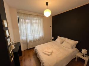 a bedroom with a large white bed with a black wall at INC apartment in villa in Bucharest