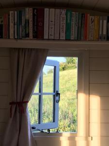 a book shelf with a window and a windowtaining at Dog friendly Beautifully furnished Shepherds Hut set in the Kent Countryside in Aldington
