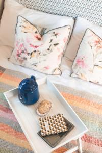 a white couch with a table with a cup of coffee and a cookie at Dog friendly Beautifully furnished Shepherds Hut set in the Kent Countryside in Aldington