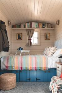 AldingtonにあるDog friendly Beautifully furnished Shepherds Hut set in the Kent Countrysideのベッドルーム1室(カラフルな毛布付きのベッド1台付)