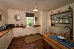 uma cozinha com armários brancos e uma mesa de madeira em Gatehouse, Bridge of Balgie, Glenlyon 