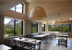 um restaurante com mesas e cadeiras e janelas grandes em Explora en El Chalten em El Chaltén