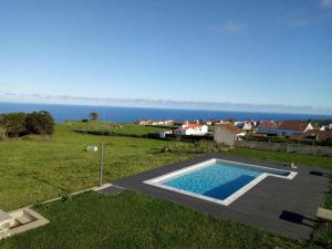 a swimming pool in a field with the ocean in the background at Casas do Forneiro A Casa Para 2 Pessoas in Nordeste