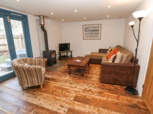 a living room with a couch and chairs and a television at Grove Lodge in Penzance