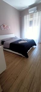Schlafzimmer mit einem Bett und Holzboden in der Unterkunft Tindaro Home in Catania