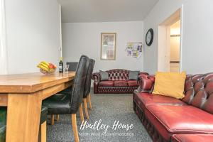 a living room with a table and a leather couch at Hindley Serviced Accommodation in Hindley