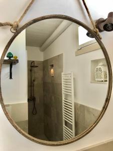 einen runden Spiegel im Bad mit Dusche in der Unterkunft RIFUGIO Salentro in Botrugno