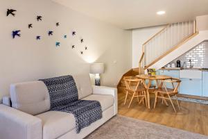 a living room with a couch and a table with birds on the wall at Casa das Andorinhas in Câmara de Lobos