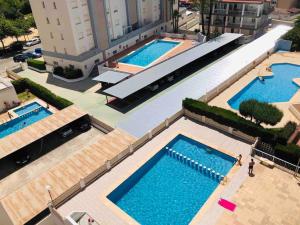 - une vue de tête sur trois piscines dans un bâtiment dans l'établissement Apartamento Gandia muy cerca de playa con piscina, à Playa de Gandia