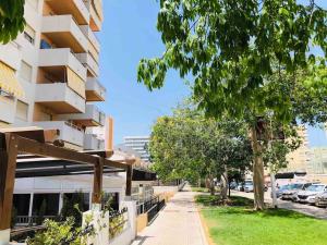 un trottoir devant un bâtiment avec un arbre dans l'établissement Apartamento Gandia muy cerca de playa con piscina, à Playa de Gandia