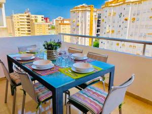 une table bleue avec des chaises et des assiettes sur un balcon dans l'établissement Apartamento Gandia muy cerca de playa con piscina, à Playa de Gandia