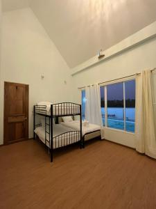 a bedroom with two bunk beds and a large window at The PaVillu de Pool Villas in Samut Songkhram