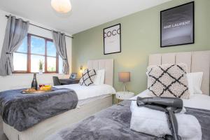 a bedroom with two beds and a chair in it at 4 Bedroom Detached House - Central MK - Free Parking, Fast Wifi and Smart TVs with Sky TV and Netflix by Yoko Property in Milton Keynes