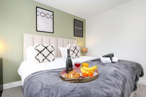 a bed with a tray of food and a bottle of wine at 4 Bedroom Detached House - Central MK - Free Parking, Fast Wifi and Smart TVs with Sky TV and Netflix by Yoko Property in Milton Keynes