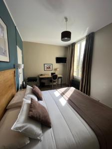 una camera da letto con un grande letto con cuscini sopra di Hotel Des Cedres a Orléans