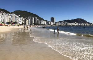 una playa con gente parada en el agua y edificios en ao lado do mar luxo In Copacabana, en Río de Janeiro
