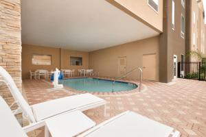 a patio with a pool and chairs and a building at Country Inn & Suites by Radisson, Katy (Houston West), TX in Katy