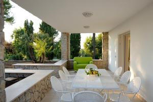 un patio con tavolo, sedie e sedia verde di AMORE RENTALS - Resort Ravenna - The Villa a Massa Lubrense