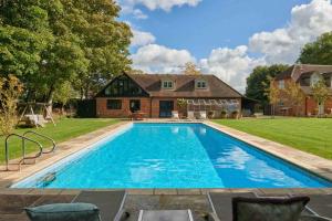 a large swimming pool in front of a house at Hollyhock Lodge in Buckinghamshire