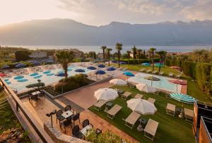 - une vue sur la piscine bordée de chaises et de parasols dans l'établissement Hotel Royal Village, à Limone sul Garda