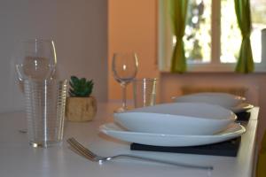 einen Tisch mit zwei weißen Tellern und Weingläsern in der Unterkunft Green Spot in Riva del Garda