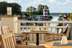a table and chairs on a balcony with a lighthouse at Precise Resort Hafendorf Rheinsberg in Rheinsberg