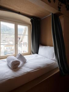 ein Bett mit Handtüchern darauf vor einem Fenster in der Unterkunft Peanut Medieval Lodge in Saint-Ursanne