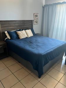 a bed with a blue comforter and pillows on it at L’Escalier Cabanas 510 in Amanzimtoti