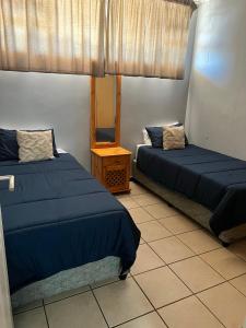 two beds in a room with blue sheets and a table at L’Escalier Cabanas 510 in Amanzimtoti