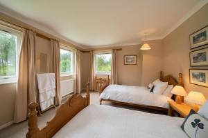 a bedroom with two beds and two windows at Lochs Lodge, Glenlyon, Perthshire 