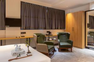 a room with two chairs and a desk and a bed at Hotel Padmawati Grand in Nānded