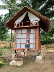 a woman is sitting in a tiny house at Manariwa - Exclusive Camp site in Tanay