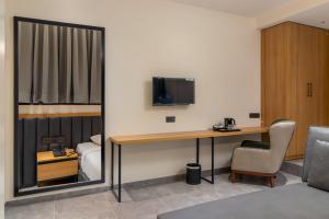 a room with a desk with a bed and a television at Hotel Padmawati Grand in Nānded