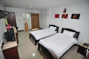 um quarto com duas camas e uma tv nele em Man u Apartment em Chaiyaphum